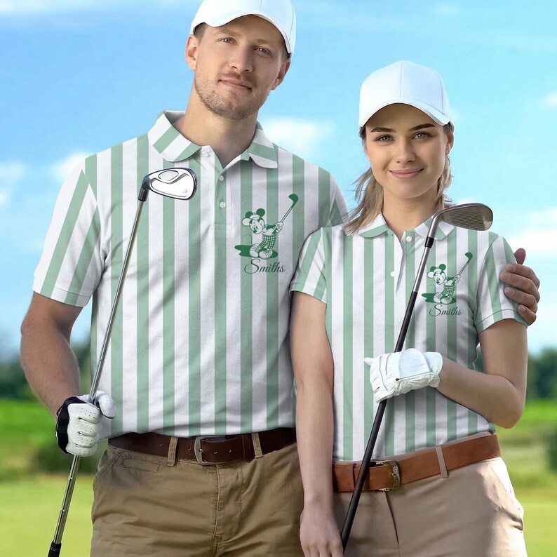 May include: Matching green and white striped golf shirts with a cartoon graphic and the name "Smiths". The shirts have a collared neckline and are paired with khaki pants and a brown belt. Both individuals are wearing white golf hats.
