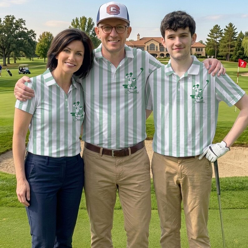 May include: Three people wearing matching green and white striped polo shirts with a Mickey Mouse graphic and the name "Smiths" on the chest. One person is wearing a baseball cap. They are standing on a golf course.