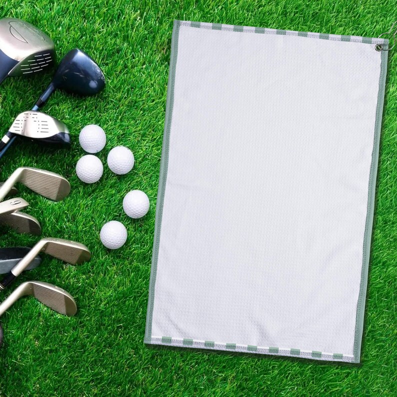 May include: A golf scene featuring golf clubs, golf balls, and a white golf towel with a green border. The items are arranged on a vibrant green grass surface, creating a clean and organized display.