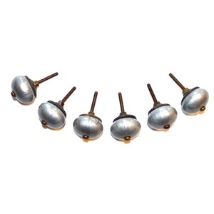 May include: Six silver cabinet knobs with a brushed finish and a brass accent. The knobs are arranged in a semi-circle on a white background.