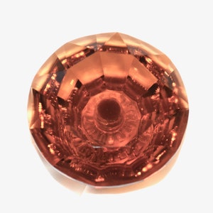May include: A round, faceted, orange-brown gemstone with a deep, dark center.