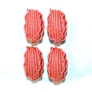 May include: Four red ceramic corn on the cob drawer pulls. Each pull is shaped like a corn cob with the husks and kernels sculpted in detail.