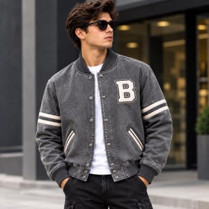 Jaqueta Varsity Masculina de Couro Cinza Carvão, Patch com a Letra B e Estampa "Better Days Ahead" nas Costas