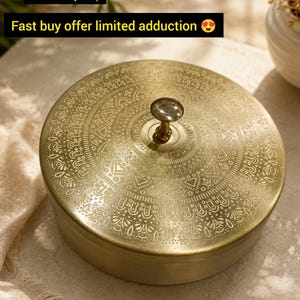 Op de afbeelding: Een ronde masala-doos van messing met een ingewikkeld geëtst patroon op het deksel en een centrale knopgreep. De tekst op de afbeelding luidt: Mini special box brass masala, Best sell my shop, Fast buy offer limited adduction.
