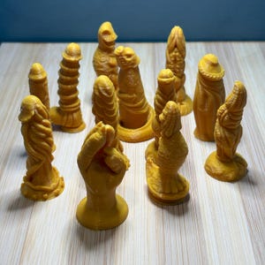 Könnte beinhalten: Eine Sammlung verschiedener gelb-oranger Skulpturen, jede mit einem einzigartigen Design. Die Sammlung umfasst Skulpturen mit gerippten, spiralförmigen und strukturierten Oberflächen. Die Objekte sind auf einer hellen Holzoberfläche angeordnet.