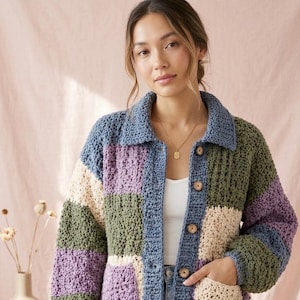May include: A patchwork crochet jacket in shades of blue, purple, green, and beige. The jacket has a collared neckline, wooden buttons, and pockets. The woman is wearing a white top underneath the jacket.