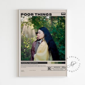 May include: A framed movie poster for "Poor Things" with a beige background. The poster features two people in a natural setting. The woman has long black hair and wears a yellow dress. The poster includes the film's title, director, and a rating.