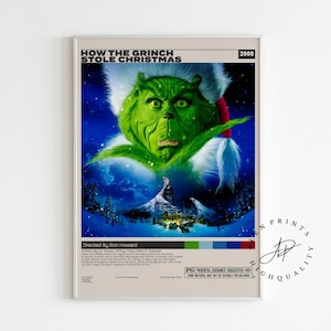 Puede incluir: Un póster enmarcado de la película "Cómo el Grinch robó la Navidad" (2000). La cara verde del Grinch está centrada, con una escena de montaña nevada debajo. El póster tiene un borde beige y texto arriba y abajo.