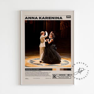May include: A framed poster for the film "Anna Karenina" (2012) features a couple dancing on a stage. The woman wears a black gown, and the man is in a white suit. The poster has a neutral background with text.