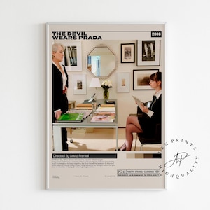 May include: A framed movie poster for "The Devil Wears Prada" featuring two women in a modern office setting. The poster has a neutral color palette with the movie title at the top and the year 2006. The poster includes the director's name and a rating.
