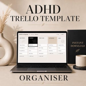 May include: A laptop screen showing an ADHD Trello template, with the words "ADHD Trello Template" and "Organiser" displayed. A black notebook with "Instant Download" is on the right. A white vase and a cup are also visible.