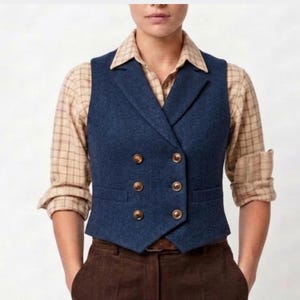 Könnte beinhalten: Eine zweireihige marineblaue Weste mit Fischgrätmuster, ausgestattet mit einem steigenden Revers und sechs Metallknöpfen. Die Weste wird über einem langärmeligen, beige-braun karierten Hemd mit hochgekrempelten Ärmeln und einer dunkelbraunen Cordhose getragen.