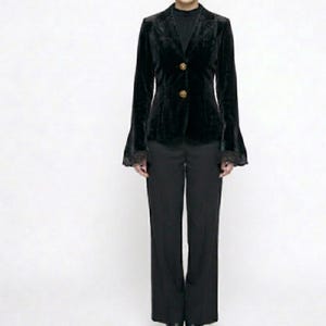May include: A black velvet blazer with bell sleeves and gold buttons, worn with black trousers. The blazer has a classic design with a tailored fit, suitable for formal events. The outfit is shown against a white backdrop.