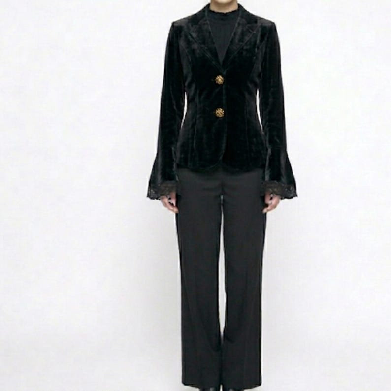 May include: A black velvet blazer with bell sleeves and gold buttons, worn with black trousers. The blazer has a classic design with a tailored fit, suitable for formal events. The outfit is shown against a white backdrop.