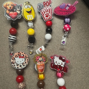 Puede incluir: Una colección de portatarjetas retráctiles con varios diseños. Los diseños incluyen un perro y un gato con un estetoscopio, un personaje de M&M, palomitas de maíz, un diseño rosa con temática médica, un diseño de Hello Kitty, una bebida floral y un Hello Kitty con la palabra "LOVE".