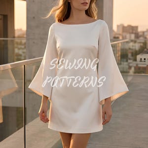 May include: Ivory-colored mini dress with wide, flared sleeves and a boat neckline. The dress features the text "SEWING PATTERNS" in a stylized font. The dress is made of a smooth, possibly satin-like fabric.