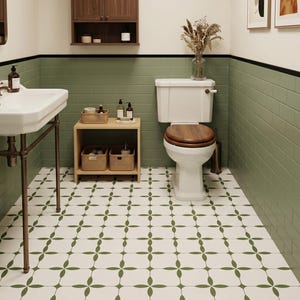 Könnte beinhalten: Ein Badezimmer mit grünen und weißen Wänden, einem gemusterten Boden und Holzmöbeln. Es gibt eine weiße Toilette mit Holzbrille, ein Waschbecken und ein kleines Holzregal mit Körben.