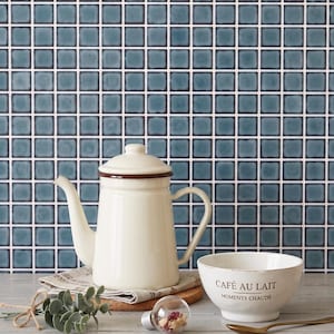 May include: A cream-colored enamel teapot with a brown rim and lid, paired with a matching cream-colored ceramic bowl featuring the text CAFÉ AU LAIT MOMENTS CHAUDS. The set includes a small glass bulb ornament and a sprig of green leaves.