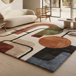 Peut inclure: Un tapis rectangulaire présentant un motif géométrique avec des lignes noires audacieuses croisant diverses formes dans des tons terre cuite, vert olive, beige et bleu ardoise sur un fond crème, créant un design visuel structuré et superposé.