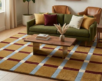 May include: A large rectangular area rug featuring a grid pattern in mustard yellow, light blue, and deep burgundy. The rug has a textured, tufted surface and covers a significant portion of the light-colored wooden floor in the living room space.