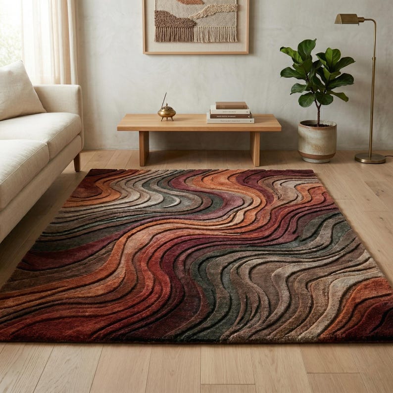 May include: A rectangular area rug featuring a textured, three-dimensional wave pattern in a gradient of warm earth tones including deep rust, burnt orange, muted brown, and charcoal gray, creating a flowing, layered visual effect across the surface.