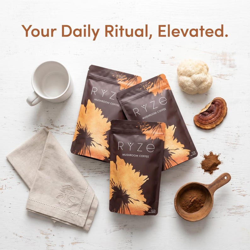 Puede incluir: Vista cenital de tres bolsas de caf&eacute; de hongos RYZE marr&oacute;n oscuro con un dise&ntilde;o de girasol, una taza blanca, una servilleta beige doblada y una cuchara de madera con caf&eacute; molido. El texto "Your Daily Ritual, Elevated." est&aacute; en la parte superior.