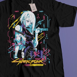 May include: Black t-shirt featuring a colorful anime-style illustration of a female character with white hair and a futuristic outfit. The shirt includes the text "LUCY" and "CYBERPUNK EDGERUNNERS" in a neon style.