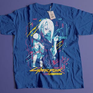May include: Blue t-shirt featuring a graphic of a female anime character with white hair and red eyes. The design includes the text "LUCY" and "CYBERPUNK EDGERUNNERS" in a futuristic font. A tag with the size "LARGE" is attached.