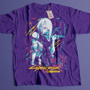 May include: Purple t-shirt featuring a graphic of a female anime character with white hair and blue accents. The shirt has the text "LUCY" and "CYBERPUNK EDGERUNNERS" in yellow and pink. A tag reads "LARGE".
