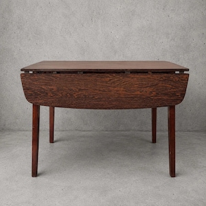 May include: A dark brown wooden drop-leaf table featuring a rectangular top with two hinged side panels that fold downwards. The table is supported by four straight legs and displays a prominent wood grain pattern across the front surface.