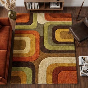 May include: A colourful, retro-style rug with a geometric pattern. The rug features curved rectangular shapes in shades of orange, brown, green, and beige. The rug is placed on a wooden floor, creating a 1970s inspired design.