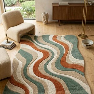 Könnte beinhalten: Gemusterter Teppich mit Retro-Design. Der Teppich hat fließende Streifen in Grün, Beige, Rost und Creme. Der Teppich liegt auf einem Holzboden, und der Raum hat eine moderne, minimalistische Ästhetik.