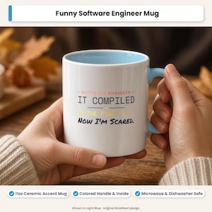 May include: A white ceramic mug with a light blue interior and handle. The front features the text: SOFTWARE ENGINEER - IT COMPILED ON THE FIRST TRY NOW I'M SCARED. The text is printed in black, yellow, and red lettering on the white surface.