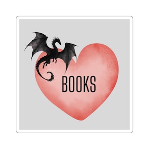 May include: A square sticker featuring a large, coral-colored heart shape centered on a light gray background. The word BOOKS is printed in black, sans-serif capital letters inside the heart. A black, winged dragon silhouette is perched on the top left edge.