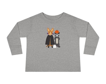 May include: A long-sleeved, grey shirt with a Halloween graphic. The graphic shows a cartoon corgi in a vampire cape, a raccoon with a pumpkin hat, and a small ghost. The shirt is made of a soft material and is suitable for children.