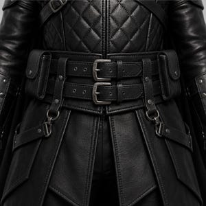 May include: A black leather jacket featuring a quilted chest panel, long sleeves, and a wide waist belt with two silver-toned metal buckles. The garment includes two attached side pouches and decorative metal hardware, including rivets and D-ring attachments.