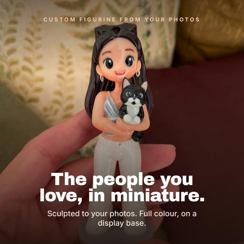 May include: A custom figurine featuring a person with long dark hair, wearing a light-colored top and white pants, holding a small black and white cat. The text reads: CUSTOM FIGURINE FROM YOUR PHOTOS. The people you love, in miniature. Sculpted to your photos.