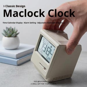 Op de afbeelding: Een beige Maclock Clock met een digitale display die de tijd, datum en temperatuur weergeeft. De klok heeft een klassiek ontwerp en beschikt over instelbare achtergrondverlichting. De tekst "Maclock Clock" staat op de klok.