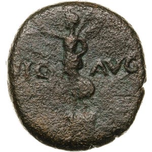 May include: A circular, dark brown, weathered bronze coin featuring a central embossed figure standing with one arm extended. The letters "AVG" are clearly visible to the right of the figure, while partial, worn lettering appears to the left.
