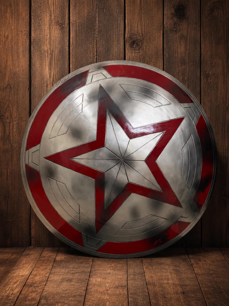 May include: A silver and red shield with a large red star in the center. The shield has a circular design with a red border and is leaning against a wooden background. The shield is approximately 24 inches in diameter.