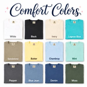 May include: A colour chart titled Comfort Colors displaying twelve folded t-shirts in various shades: white, black, ivory, lagoon blue, sandstone, butter, chambray, mint, pepper, blue jean, denim, and moss, each with a visible neck label.