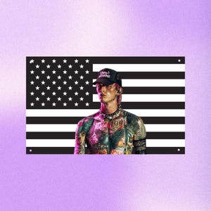 May include: A rectangular wall art piece with a black and white American flag design. A person wearing a black cap with white text, a black choker, and tattoos is positioned in front of the flag. The background is a purple gradient.