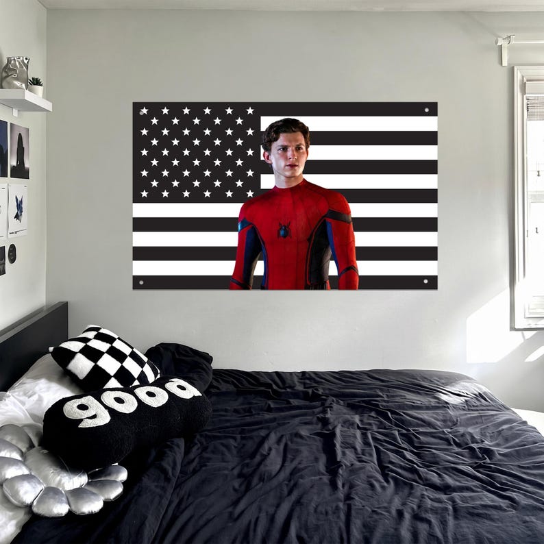May include: A wall art piece featuring a black and white American flag design with a portrait of a person in a red and blue superhero suit. The room includes a bed with black bedding and decorative pillows.