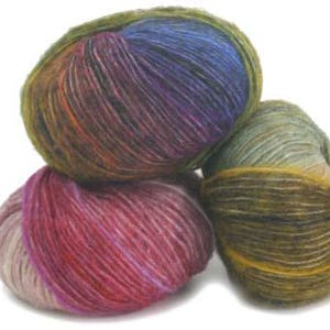 May include: Three round balls of yarn stacked together. The top ball features a blend of blue, purple, and olive green. The bottom left ball displays shades of pink, magenta, and light purple. The bottom right ball is a mix of olive green and tan.