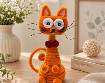 May include: A handcrafted orange cat figurine made from fuzzy pipe cleaners. The cat features large white circular eyes with black pupils, a small black nose, a red bow tie, and long black whiskers. Its tail is curled, and it has a textured body.