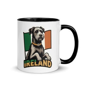 May include: White ceramic mug with a black interior and handle. The mug features a stylized illustration of a dog with a tan collar, the Irish flag, and the word "IRELAND" in green and gold.