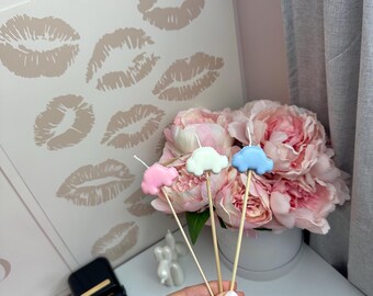 Puede incluir: Tres pequeñas velas decorativas con forma de coche en colores rosa pastel, blanco y azul claro. Cada vela está sujeta a un fino palito de madera, diseñado para colocarse sobre un pastel u otros postres con fines decorativos.
