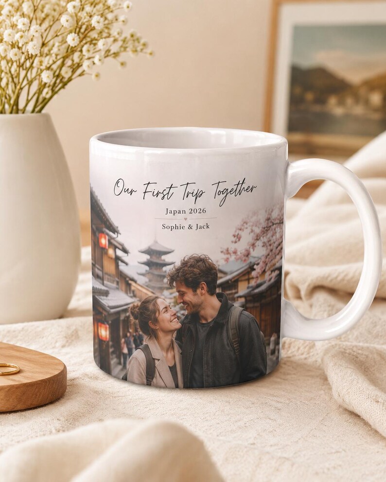 Puede incluir: Taza de cer&aacute;mica blanca con una fotograf&iacute;a de una pareja en Jap&oacute;n, con el texto "Our First Trip Together", "Japan 2026" y los nombres "Sophie & Jack". La taza tiene un asa curva y est&aacute; sobre un fondo suave y neutro.