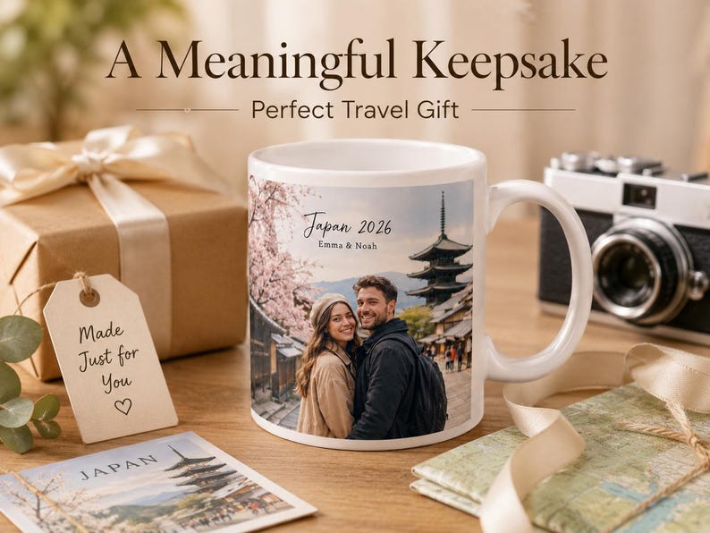 May include: White ceramic mug with a photo of a couple in Japan, a pagoda, and cherry blossoms. The mug has the text "Japan 2026 Emma & Noah." A gift box, tag, camera, and map are also in the image.