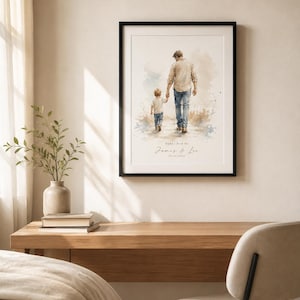 Puede incluir: Impresi&oacute;n art&iacute;stica enmarcada con una ilustraci&oacute;n en acuarela de un padre y un ni&ntilde;o caminando juntos. La impresi&oacute;n incluye el texto "Daddy and Me" y los nombres "James & Leo" con una fecha. La obra de arte est&aacute; enmarcada en un marco negro.